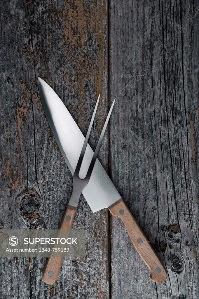 Carving knife and fork on a rustic wooden boards