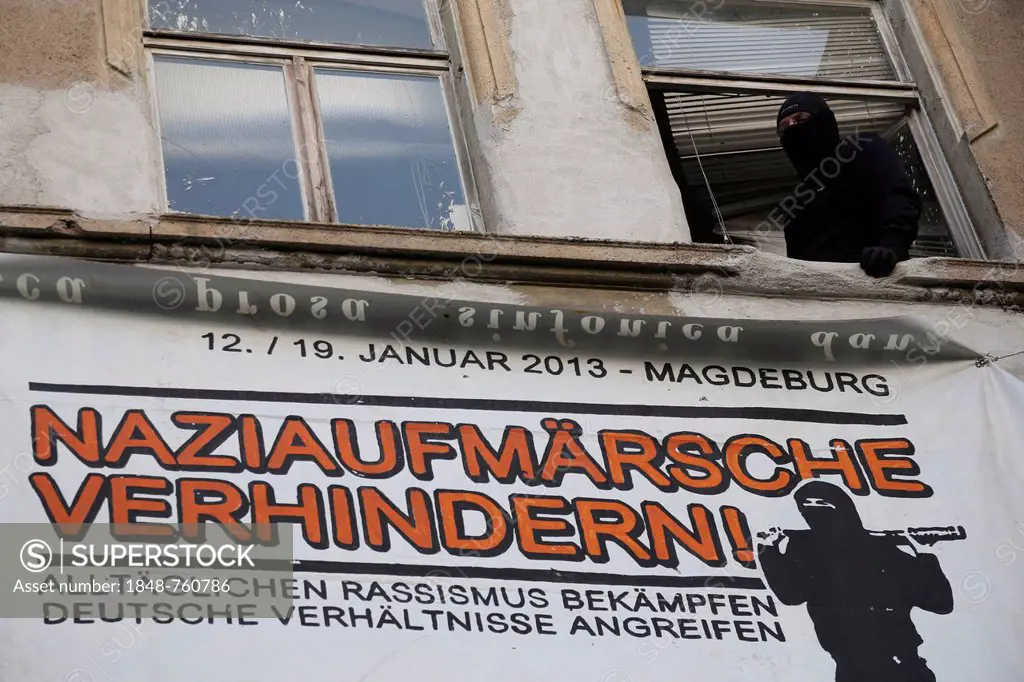 Protest against a neo-Nazi march, a masked man is standing at the window of a left-wing housing project, libertarian centre, on the route of the neo-N...