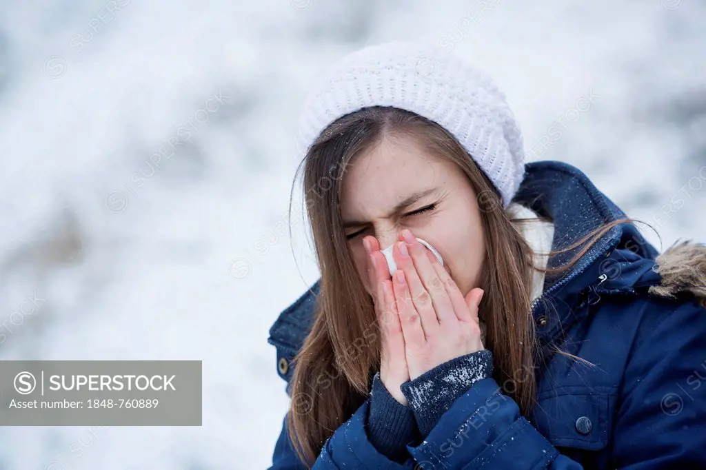 Young woman wearing winter clothes blowing her nose