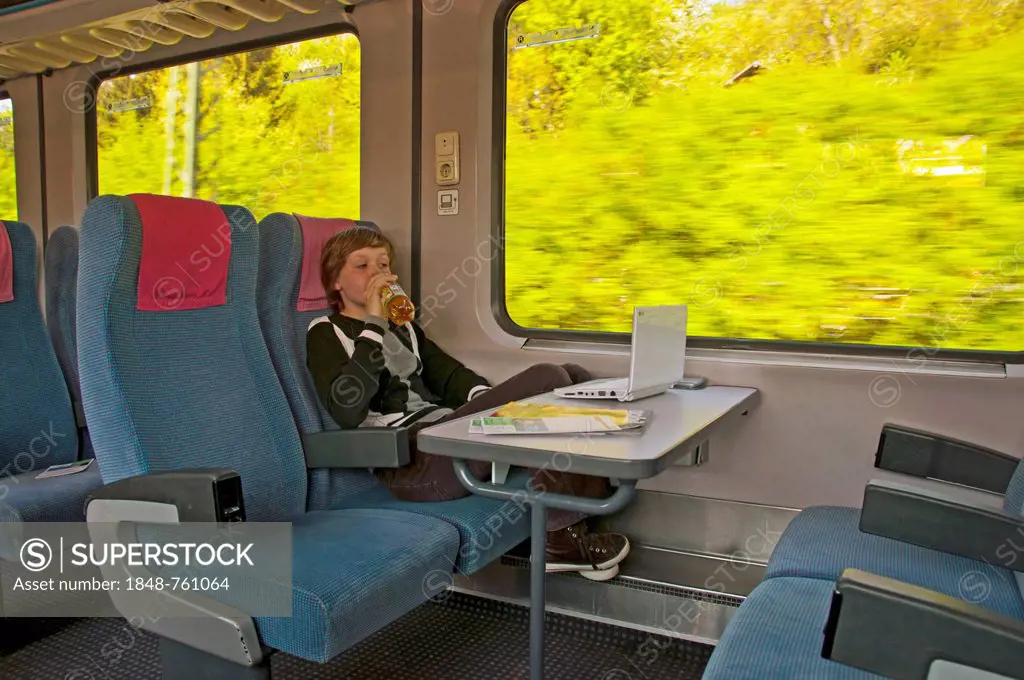 Boy, 11 years, watching a movie on his netbook whilst travelling on an Intercity train, IC, Deutsche Bahn, German railway company