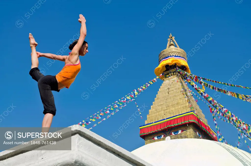 Young woman practicing yoga at Boudnanath stupa, showing the Natarajasana pose, or Lord Shiva's pose