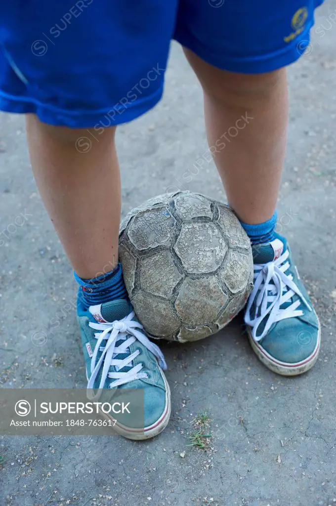 Detailed view of children legs with an old football