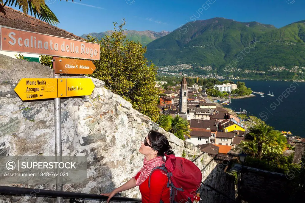 Woman looking at a signpost while hiking, Ascona, Lake Maggiore, Ticino, Switzerland, Europe