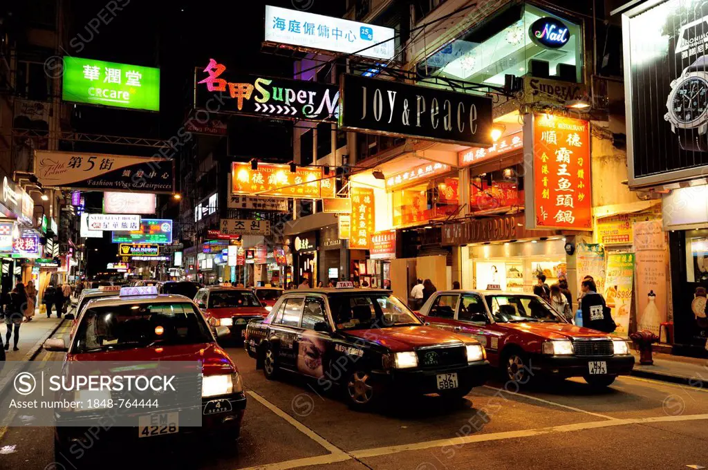 Red taxis on a street in Tsim Sha Tsui at night, Kowloon, Hong Kong, China, Asia