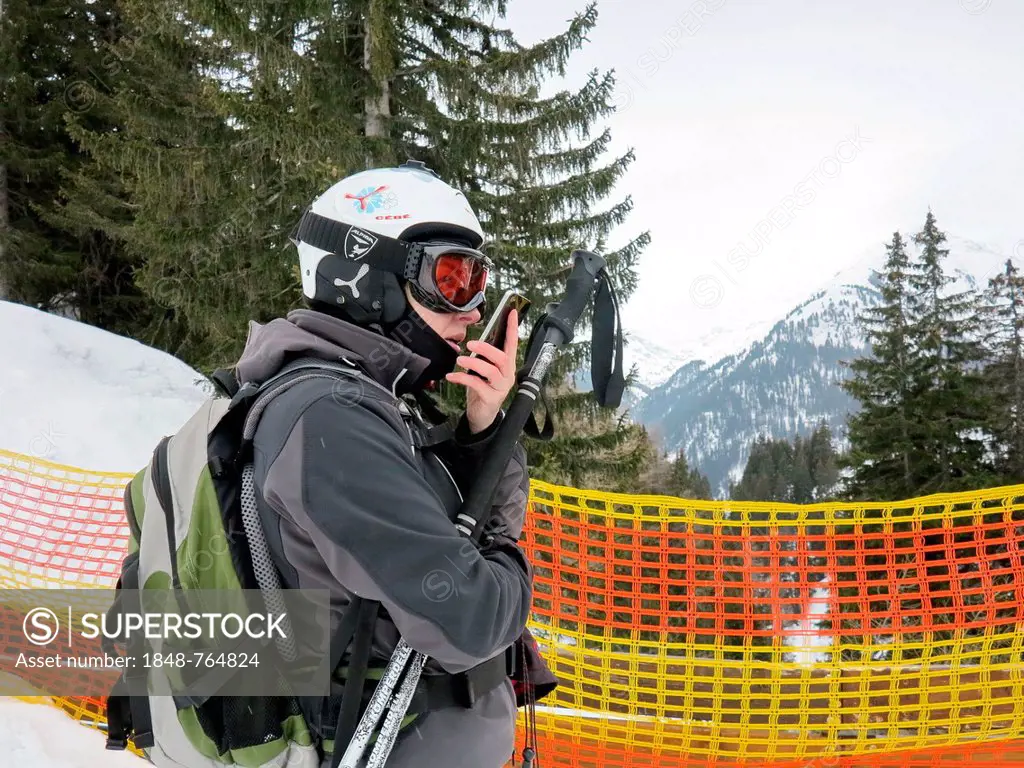 Skier on a barrier speaks in their smartphone, St. Anton am Arlberg, Tyrol, Austria, Europe