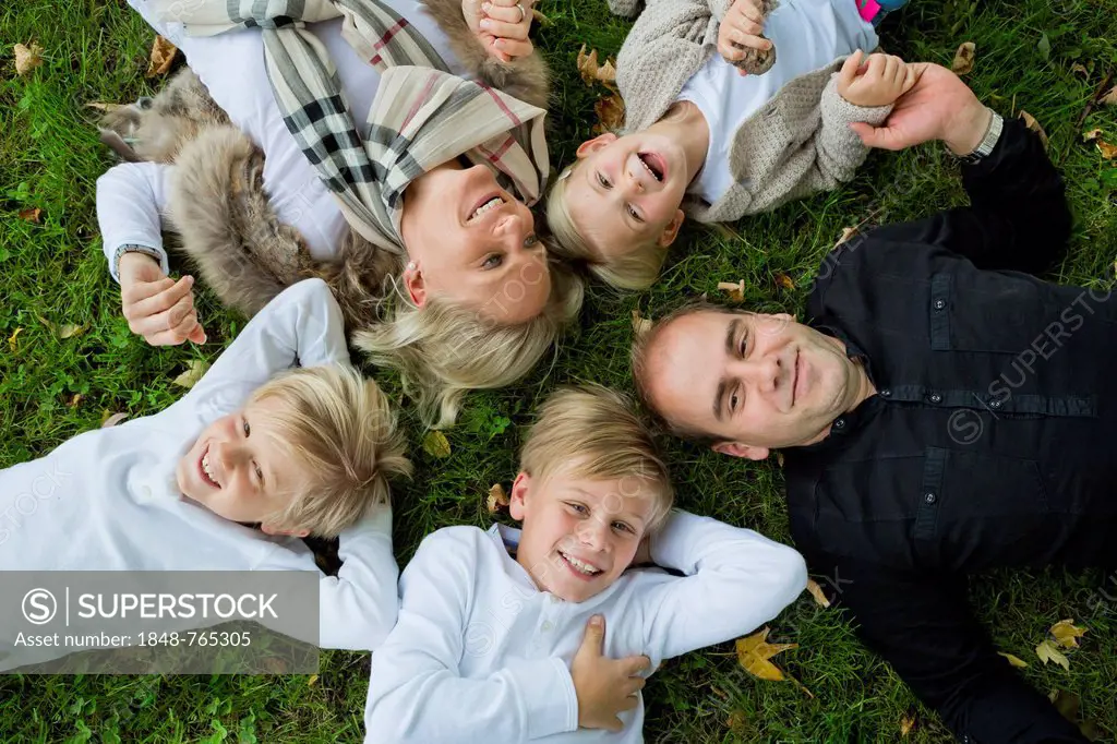 Family with three children lying on the grass
