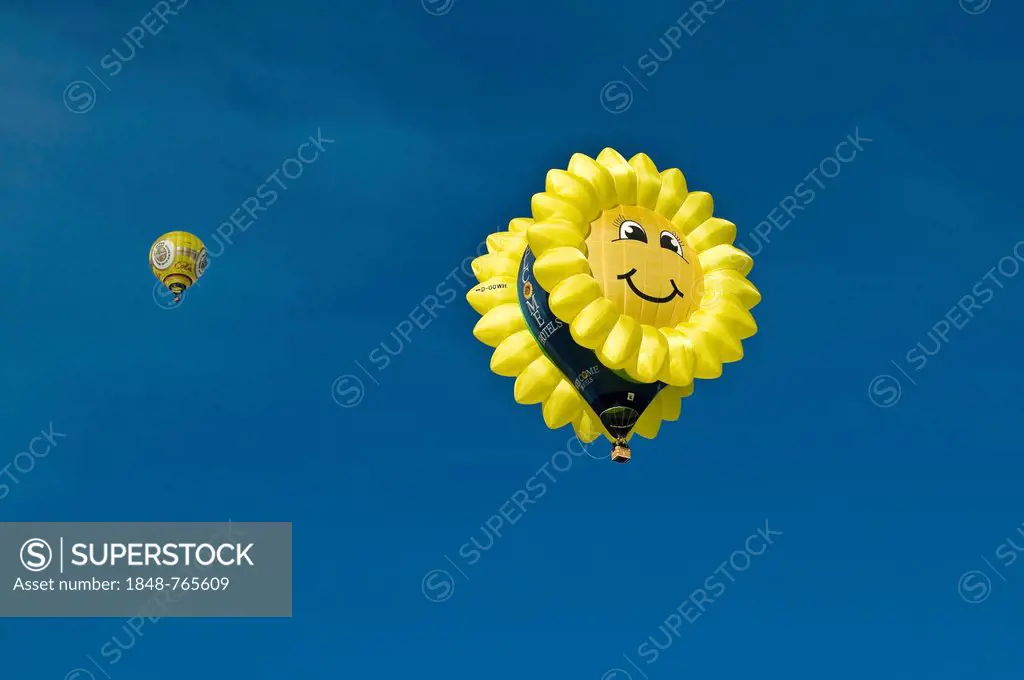 Hot air balloon in the shape of a laughing sun or sunflower against a blue sky, 12th balloon festival of Tegernsee, Montgolfiade, Bad Wiessee, Tegerns...
