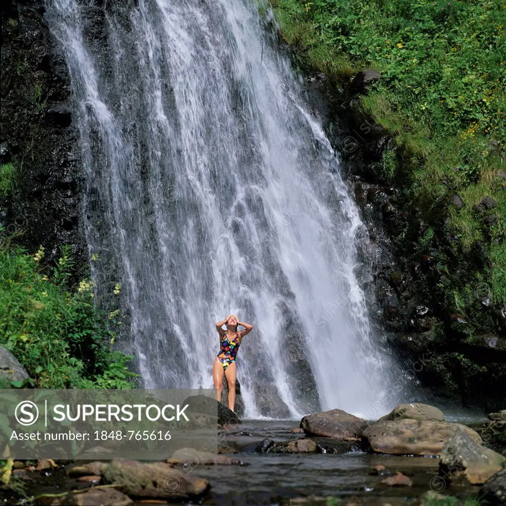 Girl bathing in a waterfall, Parc Naturel Regional des Volcans d'Auvergne, Natural regional park of Volcans d'Auvergne, Puy de Dome, Auvergne, France,...