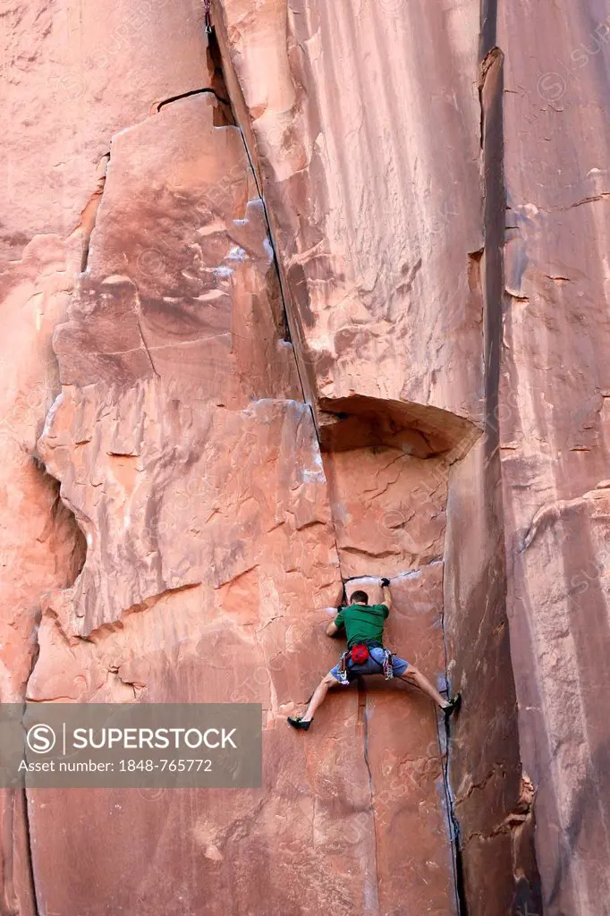 Rock climber climbing a rock wall, near Moab, Utah, USA