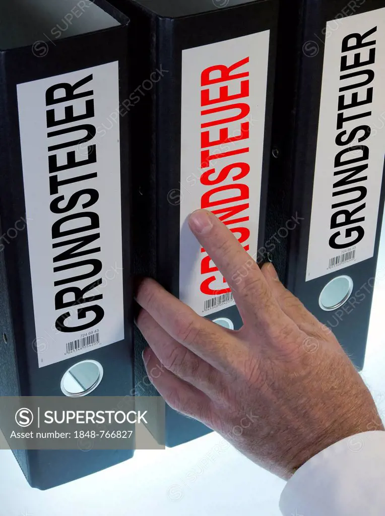 Hand reaching for file folders labeled Grundsteuer, German for land tax