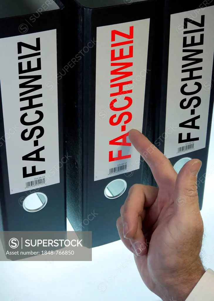 Hand pointing to file folders labeled FA-Schweiz, German for Swiss tax office