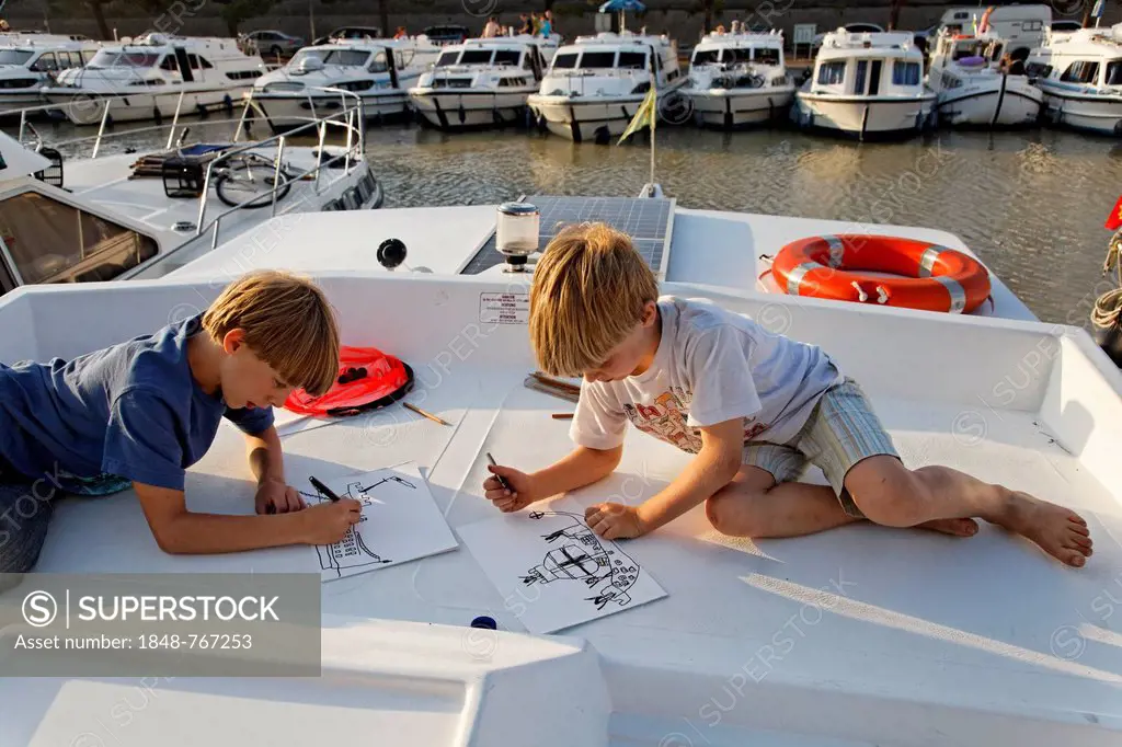 Two boys drawing on a houseboat in a harbour on the Canal du Midi
