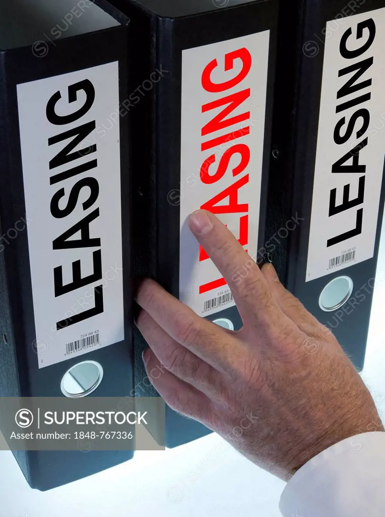 Hand reaching for a ring binder labelled LEASING