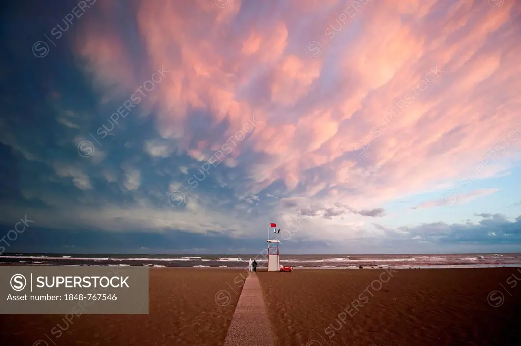 Moody clouds with the afterglow of sunset by the sea with an observation tower