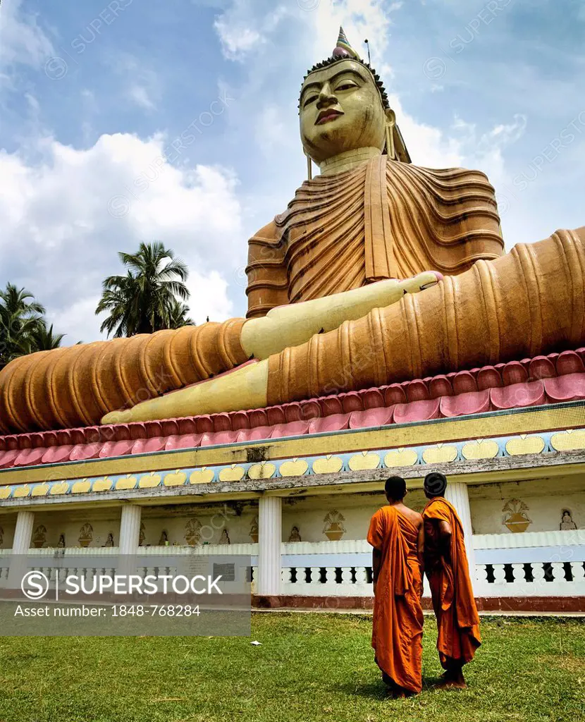Monks standing in front of giant Buddha statue, Wewurukannala Vihara temple