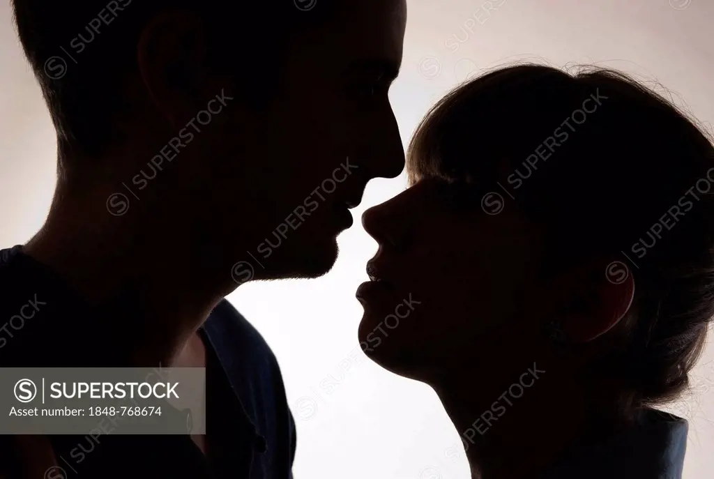 Young couple looking face to face tenderly, backlit