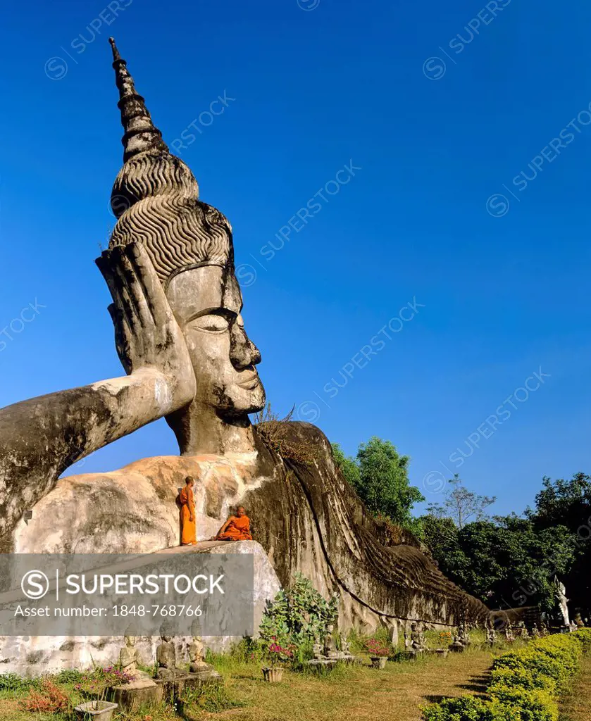 Reclining Buddha, monks on the sculpture, in Xieng Khuan Buddha Park, Suan Xieng Khuan