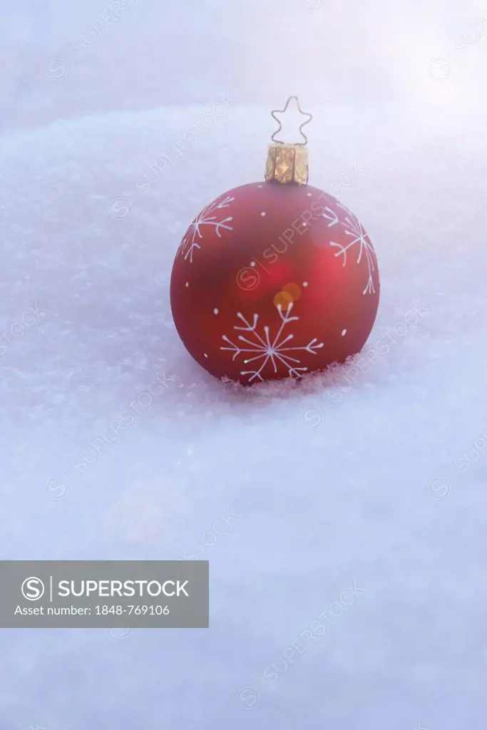 Red Christmas bauble lying in the snow