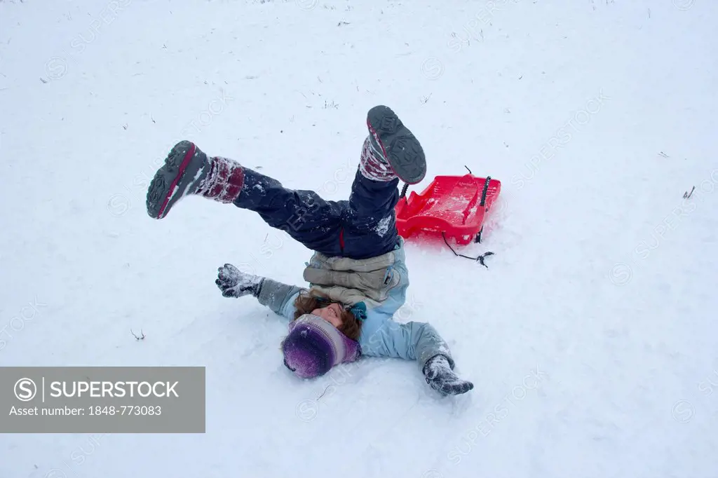 Girls rolling in the snow while sledding