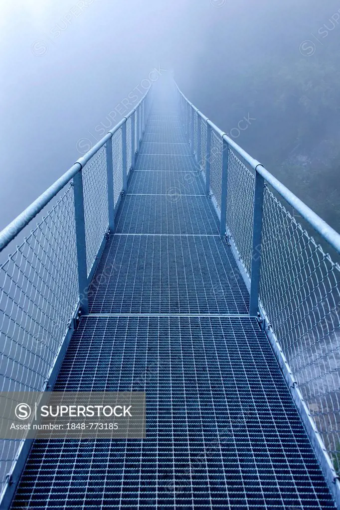 Steel bridge in the fog crossing over an Alpine stream