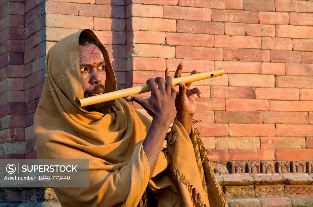 Young man playing flute at the burning ghats