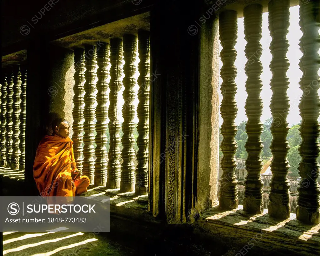 Buddhist monk sitting at a baluster window in the temple of Angkor Wat, UNESCO World Cultural Heritage Site