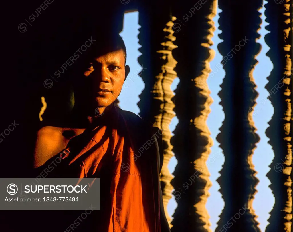 Buddhist monk in front of a baluster window in the temple of Angkor Wat, UNESCO World Cultural Heritage Site