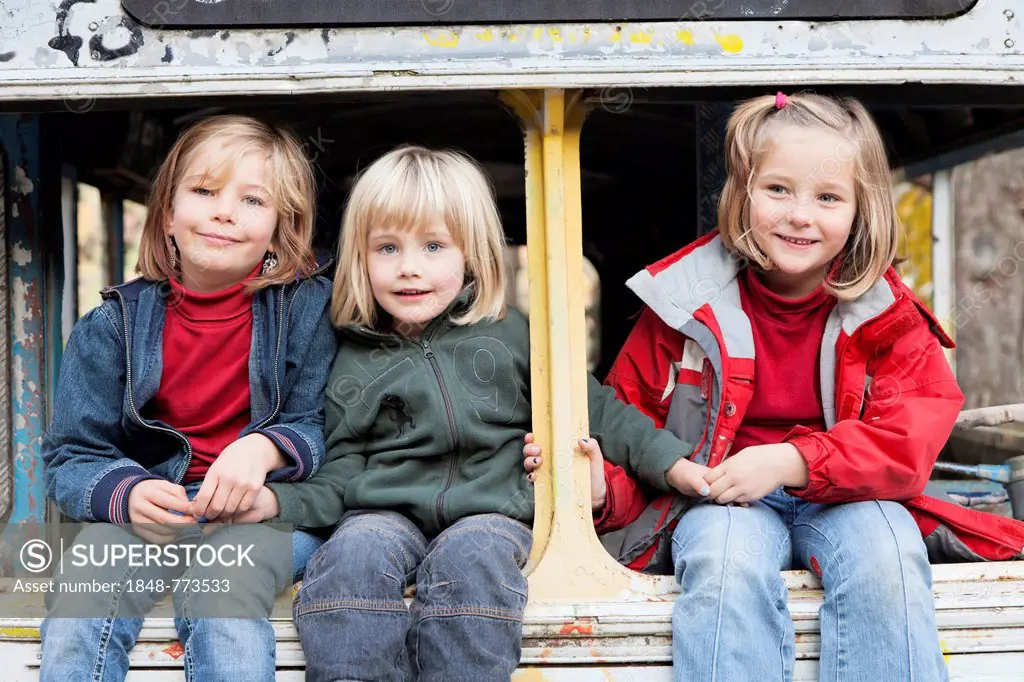 Three children sitting in a disused bus