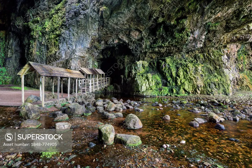 Covered bridge leading into the partly flooded with water Smoo Cave limestone cave