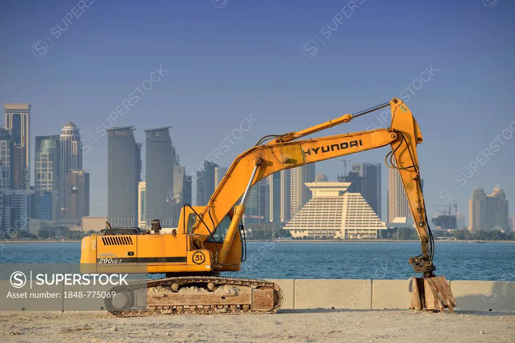 Building boom in Doha, Hyundai excavator in front of the skyline of Doha with Doha Sheraton Hotel, Four Seasons Hotel, Falcon and Pearl Towers