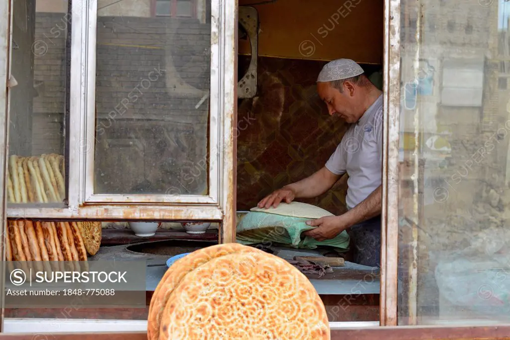 Flatbread baker in a bakery, Uyghur Muslim Quarter