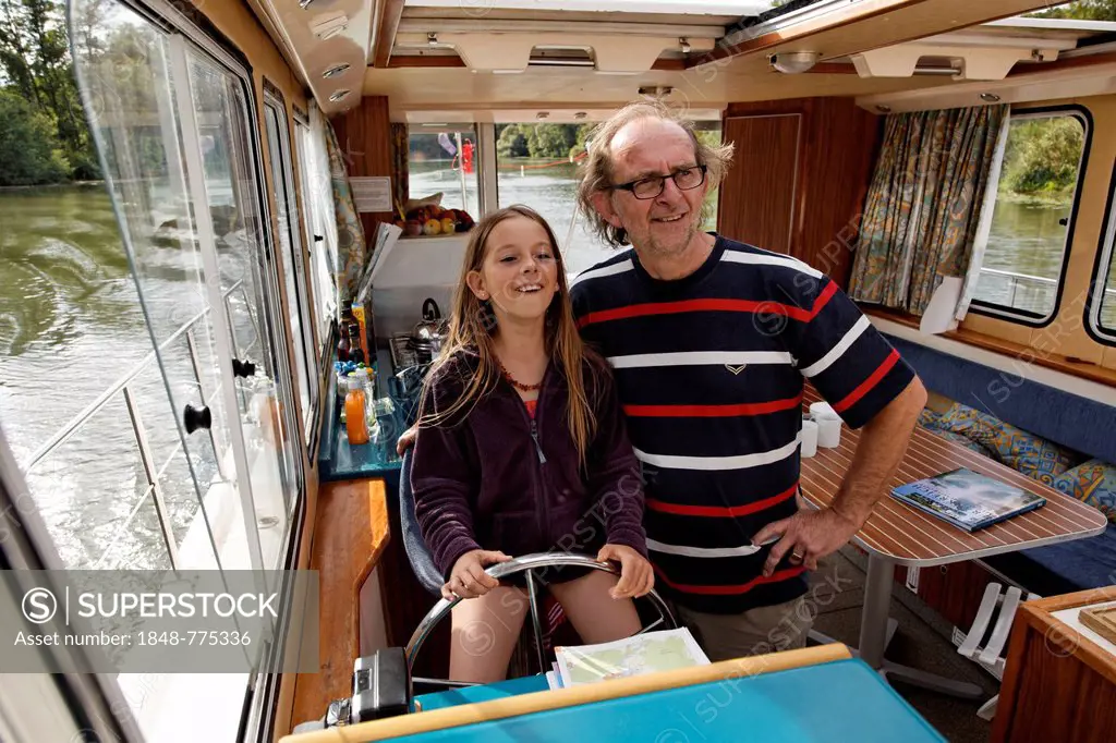 Father and daughter at the wheel of a Penichette, a houseboat on the Saône River