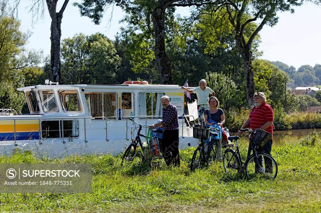 Holidaymakers in front of a house boat on the Canal des Vosges, formerly Canal de l'Est, after going shopping by bicycle