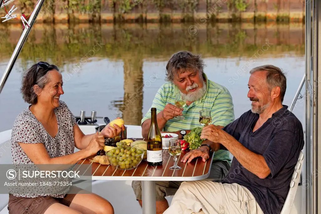 Holidaymakers enjoying dinner on a houseboat on the Canal des Vosges, formerly Canal de l'Est