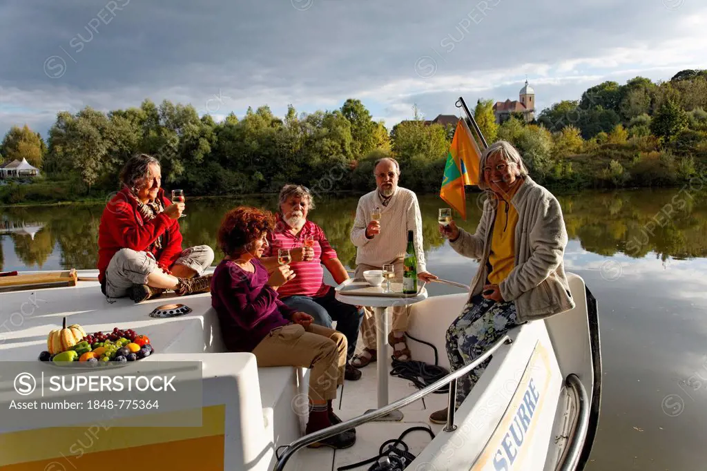 Aperitif in the evening sun, on the bow terrace of a Penichette, a houseboat on the Saône River in a quiet tributary, in the Saône Valley Marina
