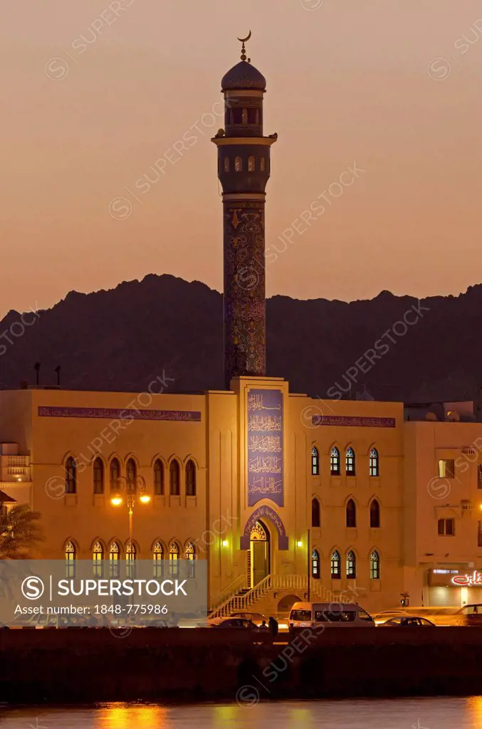 Floodlit buildings at the Corniche of Muttrah dominated by the minaret of the Rasool Azam Mosque