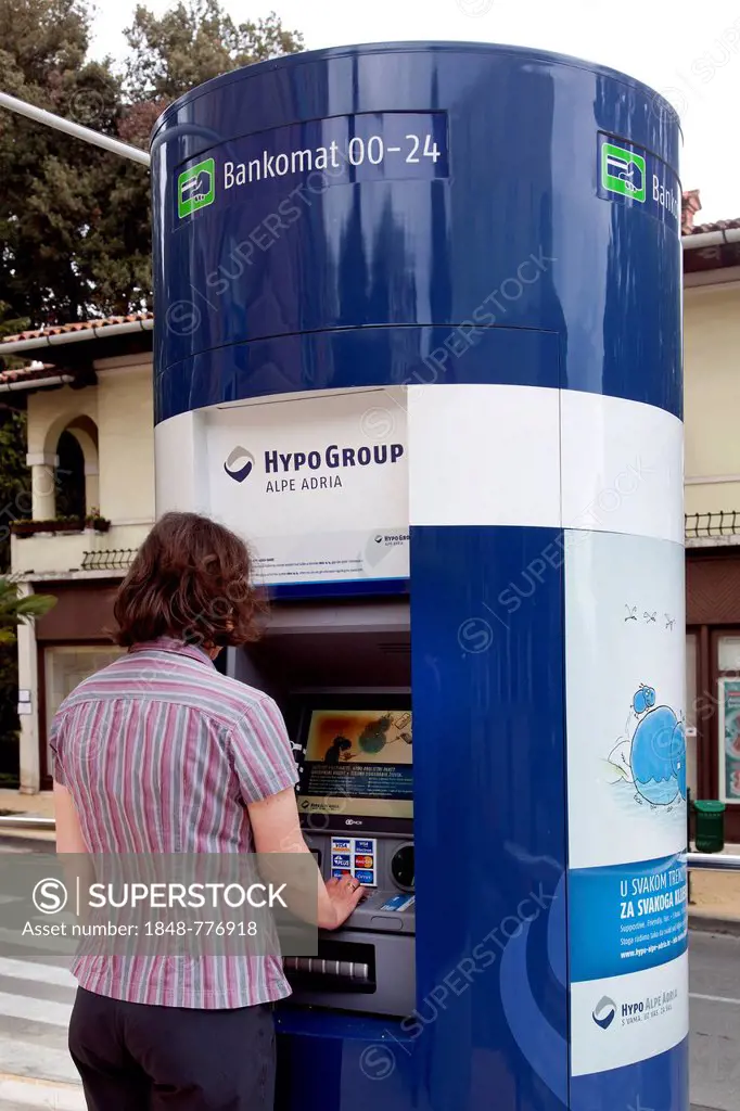 Woman extracting money from an ATM of the bank of Hypo Group Alpe Adria in Opatija, Istria, Croatia, Europe
