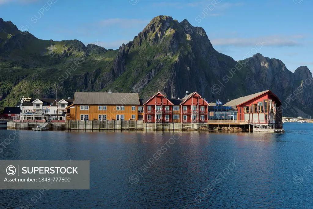 Wooden houses at the harbor entrance of Svolvaer, mountain range at back