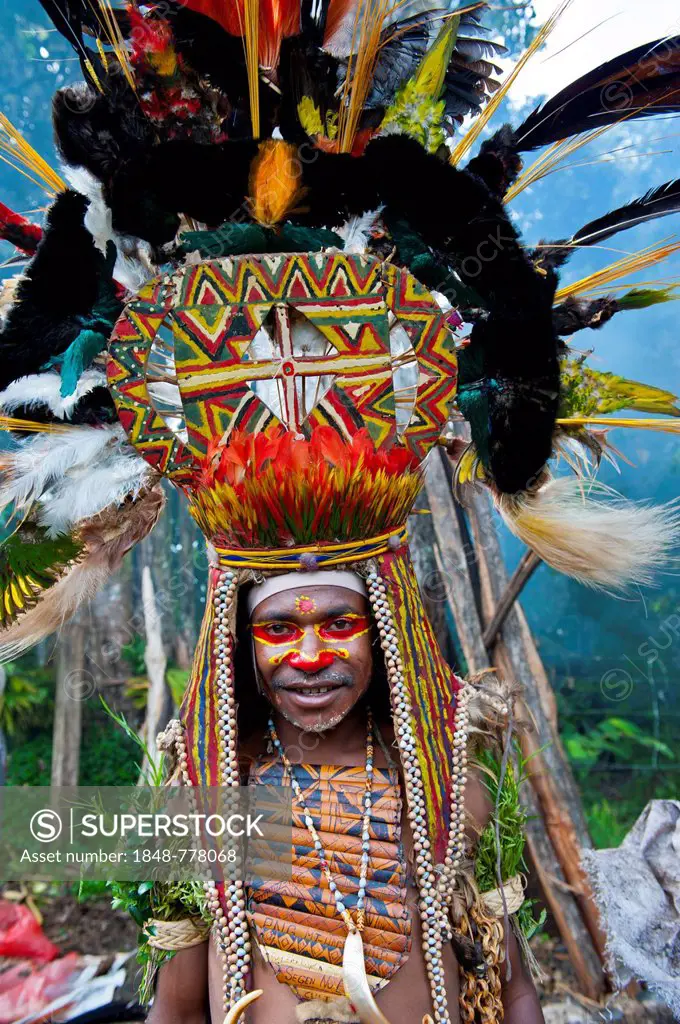 Man with a huge headdress, colourful decorations and face paint is celebrating at the traditional Sing Sing gathering in the Highlands