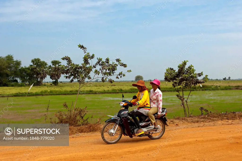 Two women riding on a motorcycle on a country road