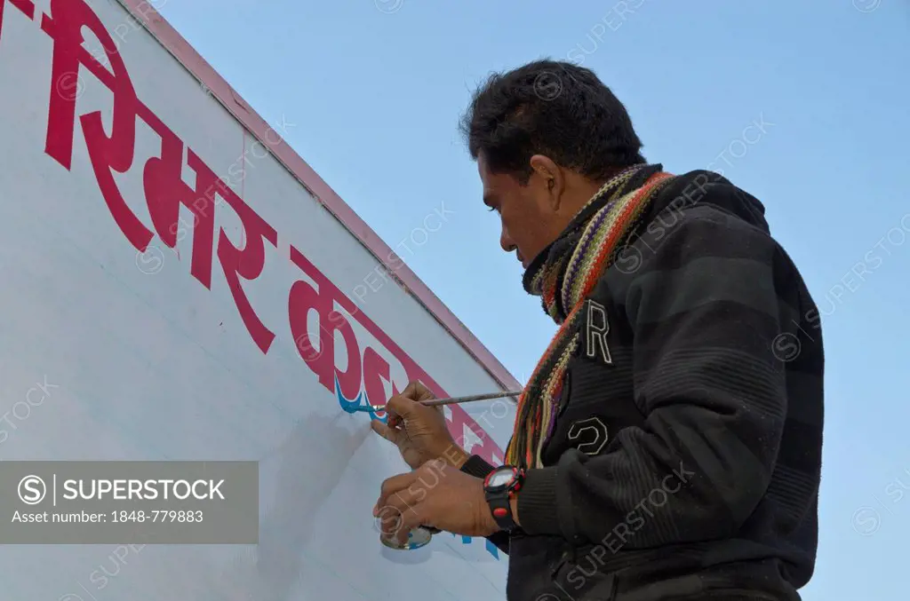 Man painting red Hindi letters on a white board