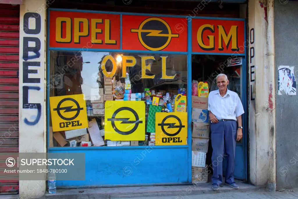 Old man is standing at a shop entrance, shop selling spare parts for Opel or Vauxhall cars, General Motors