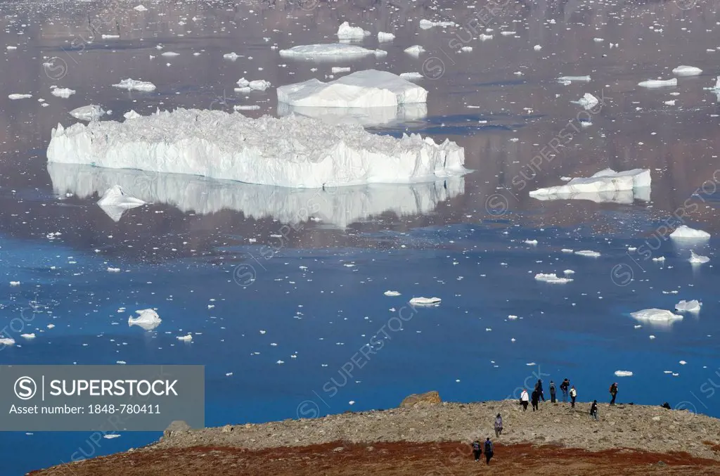 Hikers observing a very large iceberg