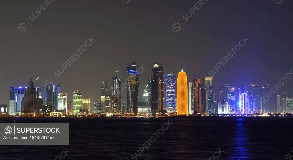 Skyline of Doha at night with the Al Bidda Tower, Palm Tower 1 and 2, the World Trade Center, Tornado Tower, Burj Qatar Tower with golden illumination...