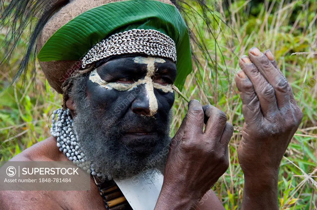 Traditionally dressed tribal chief applying face paint