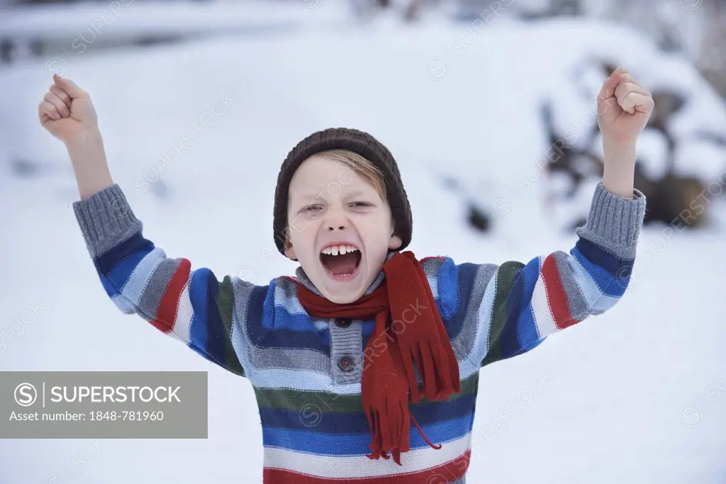 Boy in a winter sweater and a scarf, shouting with fists raised