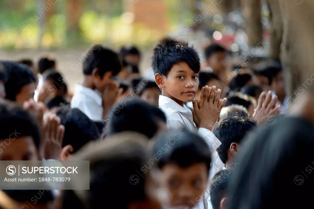 School children preparing in prayer for the donation of food and money to Buddhist monks, traditional ceremony as part of the celebrations of the Camb...