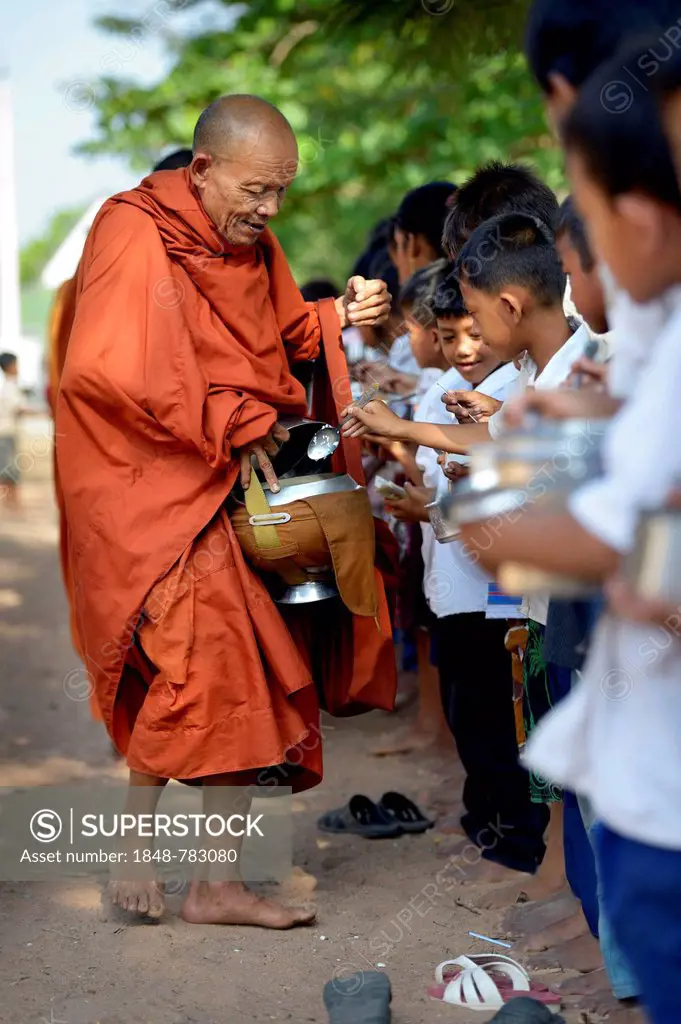 Children donating food and money to a Buddhist monk, traditional ceremony as part of the celebration of the Cambodian New Year