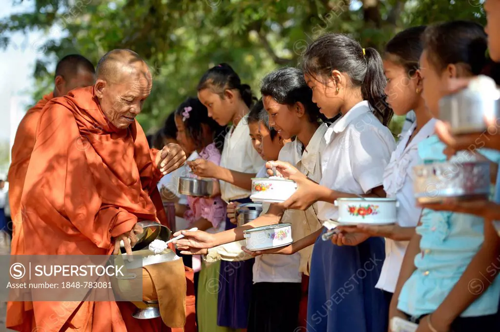 Children donating food and money to a Buddhist monk, traditional ceremony as part of the celebration of the Cambodian New Year