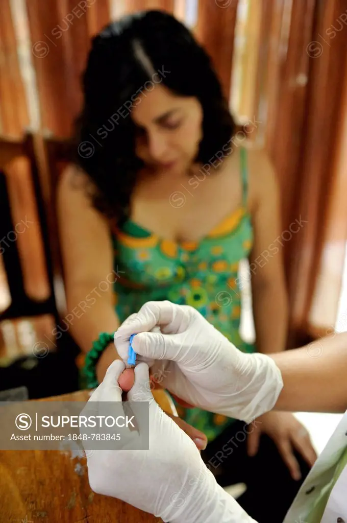 Young woman having blood removed through a needle in her fingertip for an AIDS rapid test